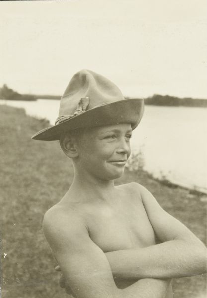 Portrait of Carl wearing a hat with his arms crossed over his chest. The St. Croix River is behind him.
