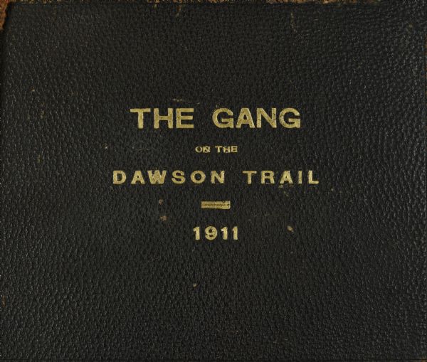 The brown leather cover of a journal compiled by Howard Greene. It is stamped in gold with the title "The Gang on the Dawson Trail, 1911."  The actual Dawson Trail follows the international boundary between Canada and USA. The locations are primarily in Canada, until the Gang arrives in Crane Lake, and then is primarily in Minnesota. 