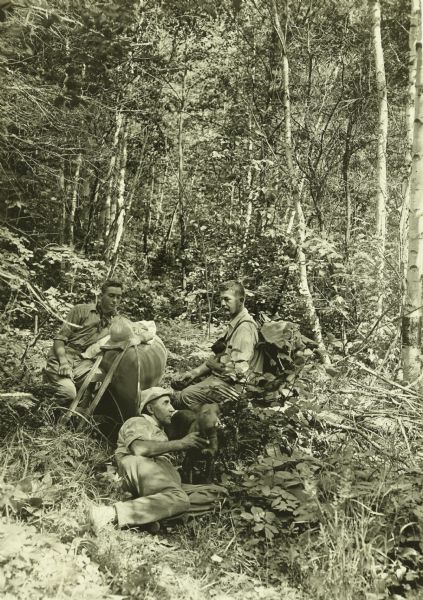The Gang stopping on the portage trail to rest. Doc Copeland is in the foreground with a dog, (possibly Diadem) and Clay Judson is on the left.