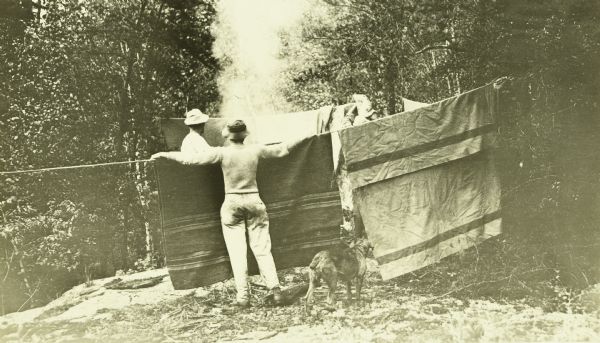 Clay Judson (in the foreground) and Doc Copeland hanging up blankets to dry after a rain shower.