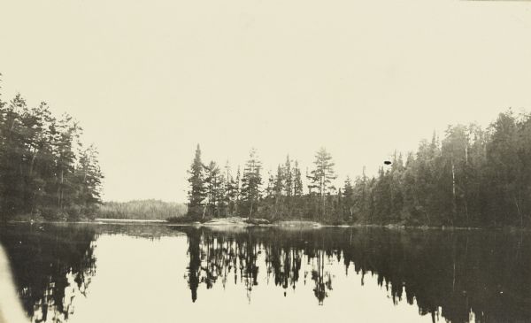View across lake towards a line of trees reflected in the waters of Burntside Lake.