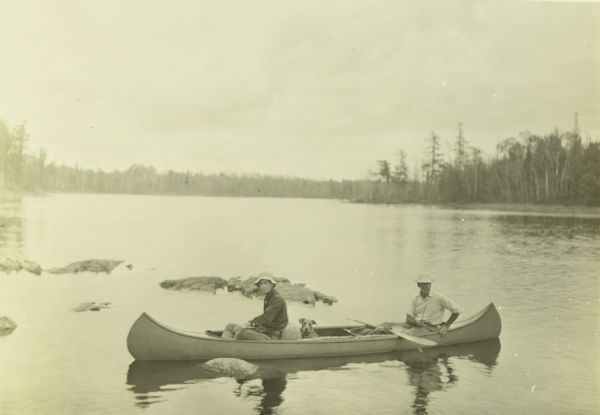 Clay, Doc Copeland, and Diadem (Di) the dog are in a canoe on what may be Namakan River or Lake.