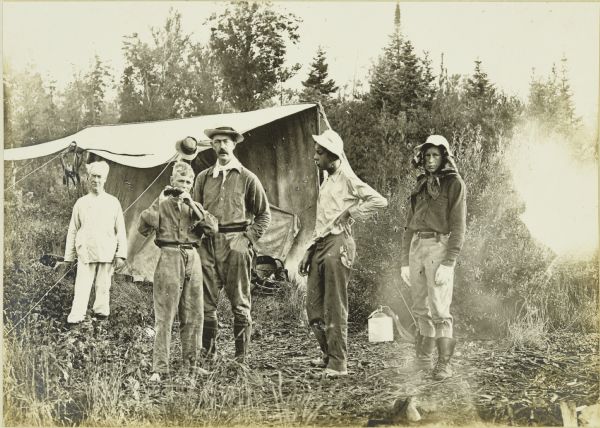 A group portrait of The Gang at Camp 2. From left to right are: an unidentified man, Carl (who appears to be holding binoculars), Bill, Howard T., and Charlie Isley.