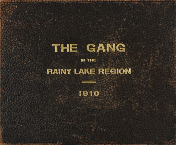The brown leather cover of the journal of Howard Greene's Rainy Lake canoe trip. The title "The Gang in the Rainy Lake Region, 1910" is stamped onto the leather in gold.