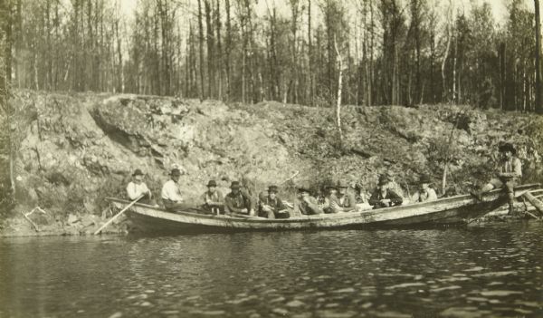 A bateau or york boat full of lumberjacks traveling down the river.