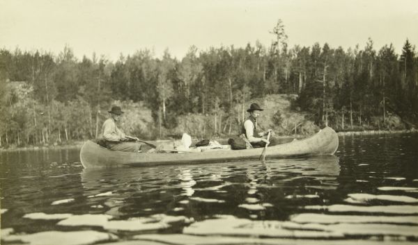 Two of The Gang paddling their canoe on a lake.