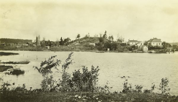 A view across the lake. There are houses and a farm on the opposite shore. 