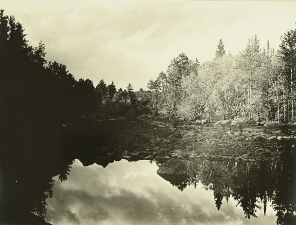 A view at the end of a bay of mirror images of trees on a lake.