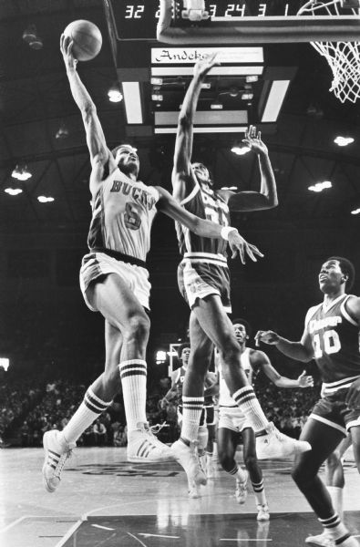 Marques Johnson of the Milwaukee Bucks drives the ball to the rim over David Thompson (33) and John Kuester (10) of the Denver Nuggets. 