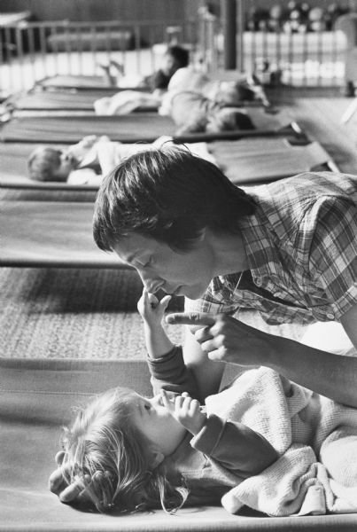 Care worker Gail Hirn plays with 23-month-old Tina Casper at Freedom House Infant Day Care Center, while other children are napping on cots in the background.