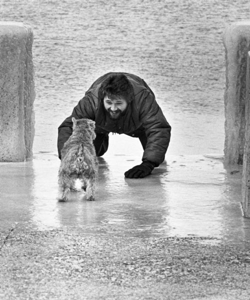 Bill Toman playing with his dog, Little Niblet, on an icy walkway at Lake Mendota.