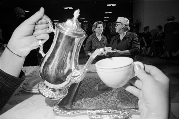 The Women's Societies of Christian Service of the Methodist Churches of Madison observed the society's 20th anniversary with a "Heritage Tea."  A silver teapot and china cup symbolize the pouring duties held by the two women in the background.  They are Maxine Wilson, wife of the district superintendent of the Methodist Church, and Florence Northcott whose husband retired last year as Methodist bishop of the Wisconsin conference.