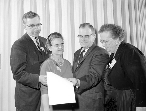 State Representative Henry C. Schadeberg of Burlington checking the text of his speech with two of his hosts before making his Lincoln Day address to the Dane County Republican Club. Others in the photograph are (left to right): Dan Neviaser, dinner chairman; Mrs. Schadeberg; and Mrs. Walter Eby, vice-chairman in charge of dinner arrangements.