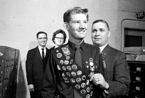 Scoutmaster Flare Fredrickson presenting the Eagle Scout award to Ronald Bessire as his parents, Dr. and Mrs. Milton C. Bessire, look on. Ronald is a member of Troop No. 27 at Sherman Avenue Methodist Church.