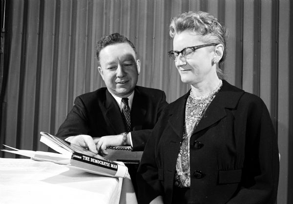Rev. Max Gabler, minister of the First Unitarian Society, shows a woman "Democratic Man," a book written by Edward C. Lindeman, during an award ceremony for Mental Health volunteers. Lindeman was a pioneer social-work educator and his book was published in 1956.