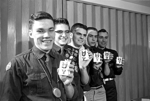 Five smiling Boy Scouts displaying their newly earned Eagle Scout badges which were awarded during a special ceremony held at the Church of Jesus Christ of Latter Day Saints at 1771 University Avenue. They are, left to right, Steve Erikson, Sterling Miller, Mark Finley Miller, Bertrand Tanner, and J. LaMar Anderson. The original caption states: "The scouts are all members of Explorer Post 101. Anderson has been the scoutmaster of the group since he first began scouting. And he worked for his Eagle Scout award right with them."