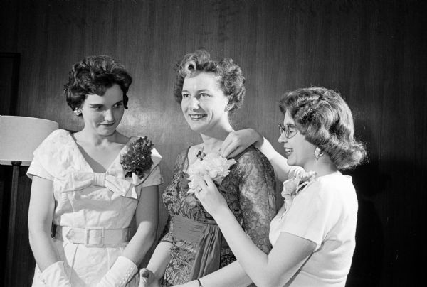 Jeanne Bloomfield, Beaver Dam, pinning a corsage on Helen Matheson who was last year's toastmistress at the Matrix banquet honoring outstanding Madison women. The event was sponsored by the Beta chapter of Theta Sigma Phi, an honorary fraternity for women in journalism. Looking on at left is Alyce Weck, Beta chapter's "own guest."