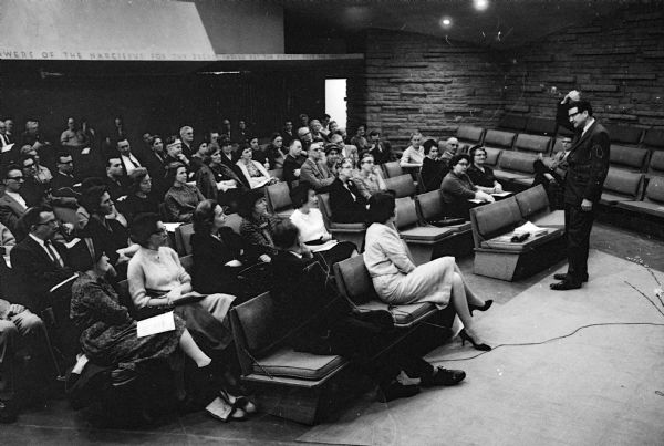Dr. Van R. Potter, assistant director of the McArdle Memorial Laboratory, argues for the Monona Terrace auditorium to a crowd of about 150 in the main hall of the Frank Lloyd Wright-designed Unitarian Meeting House in Madison.