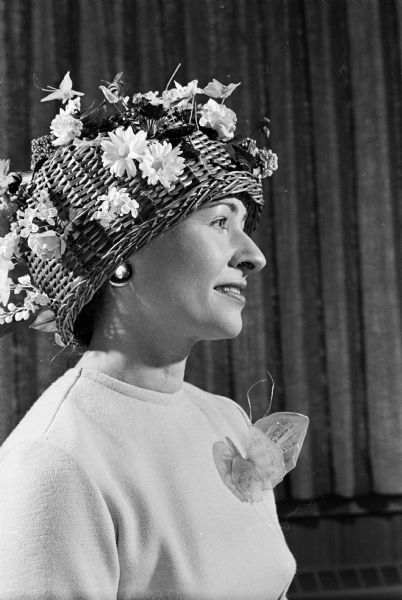 Mrs. Edwin H. (Vivian) Tallard, 1133 Edgehill Drive, wearing an inverted waste basket decorated with artificial flowers, birds, bees and butterflies at the annual Mad Hatters' Easter Parade luncheon at Blackhawk Country Club, Blackhawk Drive.