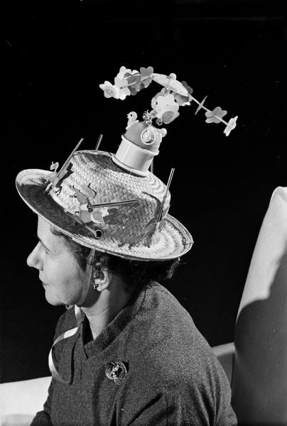 Mrs. Victor R. (Stella) Johnson of 3401 Crestwood Drive won the prize for the funniest hat at the Blackhawk Country Club Womens' Mad Hat luncheon at Blackhawk Country Club. She topped her decorated hat with a twirling toy meant to represent a carousel.