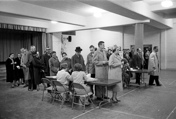 Long lines of voters gather at Midvale School for the spring 1961 election. Poll workers are sitting at two tables to register the voters.