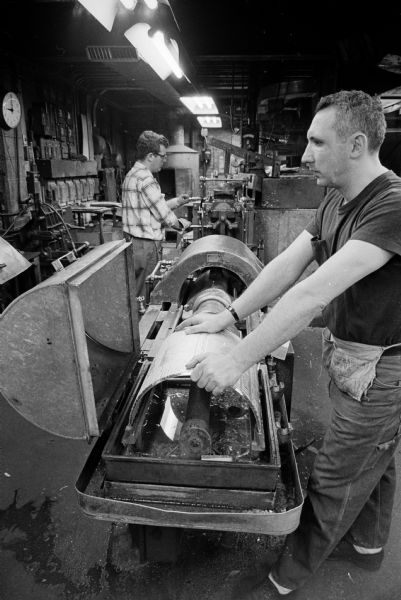 A worker at the Wisconsin State Journal building casting a curved plate for the letter press.