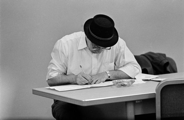 A man in a brimmed hat working on his tax form at the state tax office in the City-County building as the tax deadline nears.