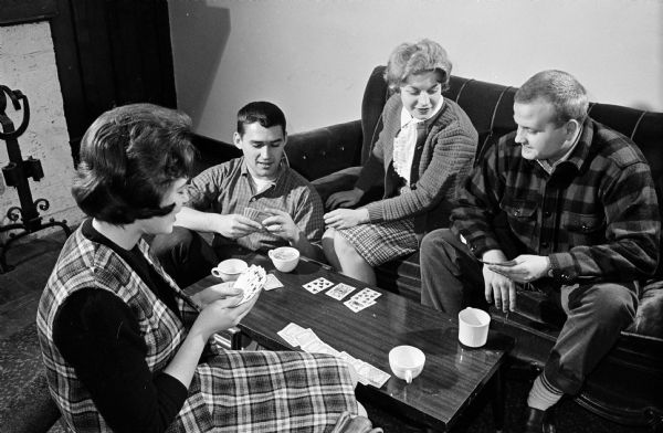 Four University of Wisconsin students are sitting around a table playing cards.