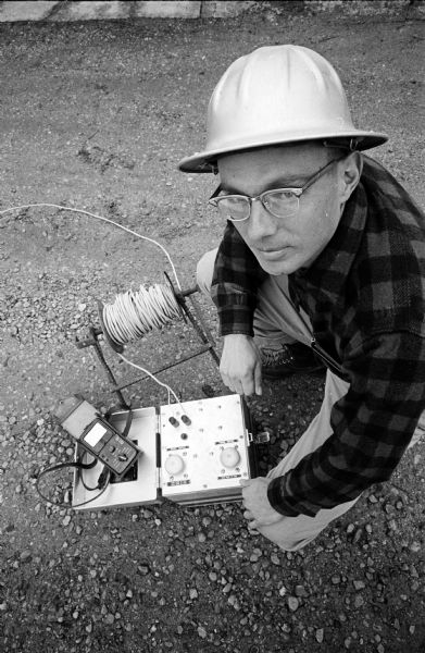 John (Cy) Ong, owner and operator of a blasting contracting service, posing with a push-button detonator ready to set off a dynamite blast.