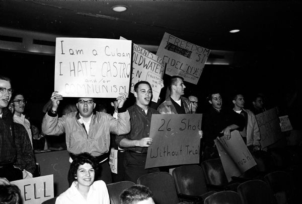 U.W. students protest a rally by the Wisconsin Socialist Club, hosts of an event at the Wisconsin Union theater supporting Fidel Castro and protesting the recent abortive American invasion of Communist Cuba. Protesting anti-Castro students at the theater carry signs. The sign on the left is being carried by Luis Valdez, a Cuban student now living in Madison. Words on the sign read: "I am a Cuban. I hate Castro and/or Communism."