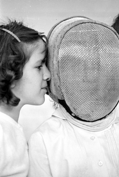 A face to face portrait of Maria Walsman, 13, pressing her nose against a protective mask worn by Minnie Schiro, 11, as they attend a demonstration of fencing at the University of Wisconsin.