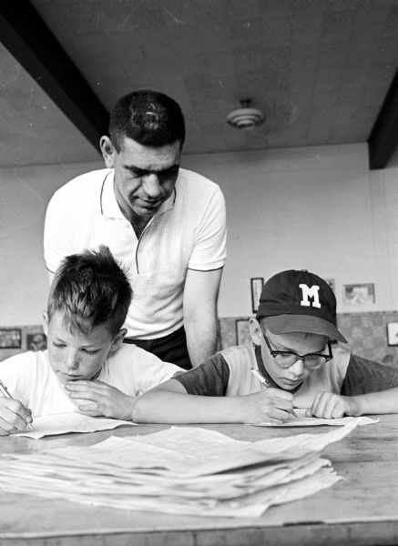 Carl Sam, center, supervising Little League baseball registration in Monona Village. Shown signing up, left to right, are Tom Pease (10) and Brad Williams (9).
