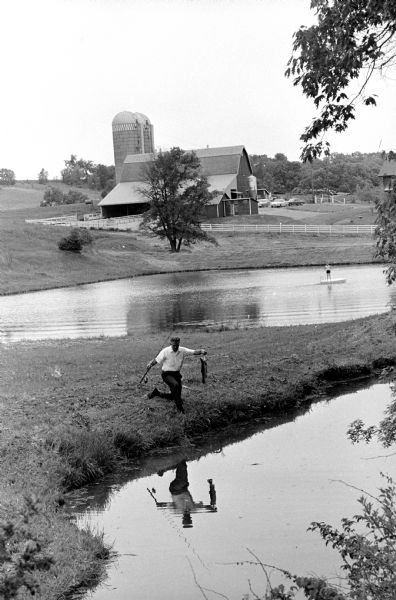 Stanley Herrling pulling in a rainbow trout from the trout pond. This is one of a series of photographs of a rural Cross Plains farm which was purchased 6 years ago by Stanley Herrling and returned to family ownership after a period of 40 years. The Herrling family has worked to build a comfortable home and restore the farm's soil, forest, and wildlife.