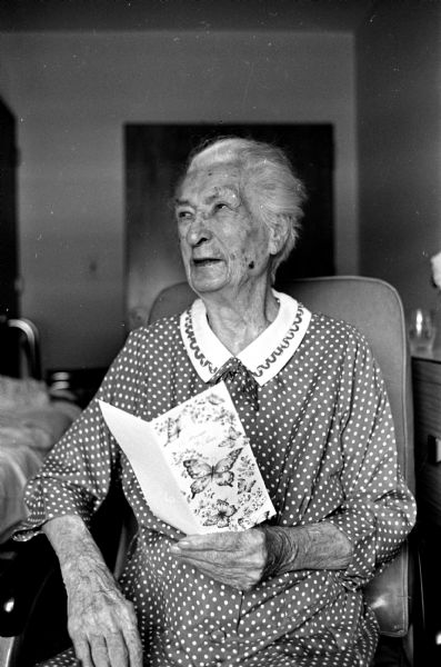 Mrs. Anna Brinkman holding a greeting card celebrating her one-hundredth birthday at the Dane County Hospital in Verona. She was born in the town of Blooming Grove.
