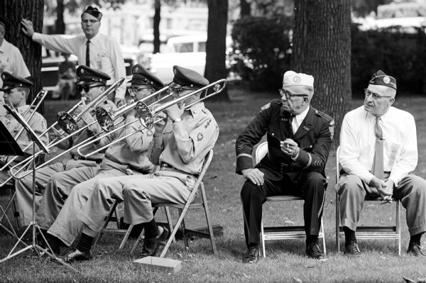 The 32nd National Guard Division band playing at the State Disabled American Veterans (DAV) plaque dedication ceremony on the State Capitol grounds as part of DAV convention in Madison. A.J. Menard, Green Bay, World War I veteran, is sitting to the right of the band.
