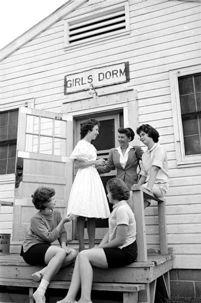 Carla Frye, Verona, models her Dane County Junior Fair 4-H style show dress for her dormitory "sisters" Sue Jalings, Oregon, seated left; Joyce Dvorak, Deerfield, seated right; and Ann Richardson, Oregon, seated on the railing. Wisconsin State Journal reporter June Dieckmann is shown standing.