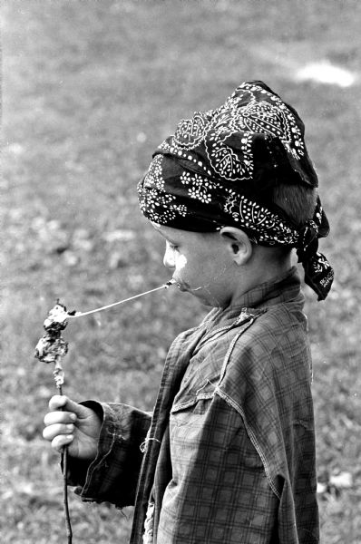 Costumed Jimmy Mick (6) eating a long strand of molten marshmallow at the Hobo Party held in Wirth Ct. Park.