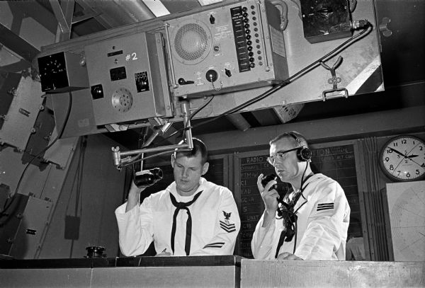 Naval reservists train at the Naval Reserve Training Center at Truax Field. A complete combat information center mockup is maintained at the training center for communication training. Shown (L-R) are Don Carey, 193 Walter St., and Dan Baumann, 4718 Odana Rd.