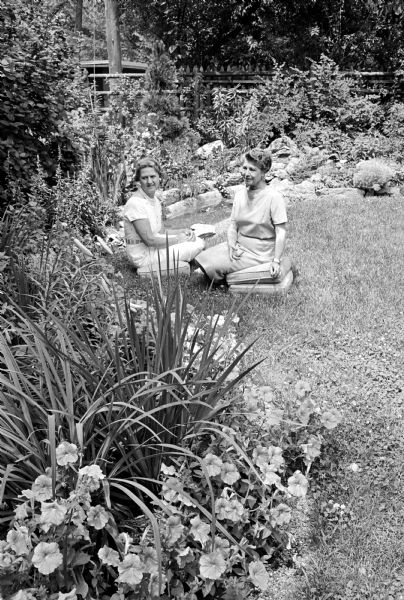 Judging flower shows requires a lot of training. Seated in a garden for the purpose of judging, are (left) Lurie Brewster Wear, a judge-in-training and (right) Dorothy Curreri, a certified flower show judge.