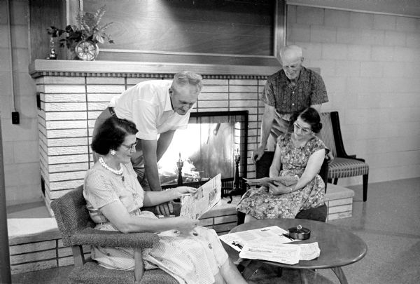 Doris and Edward Saalsaa, left, and Helen and Oscar Saalsaa, right, look over plans for their new house while posed in front of the fireplace in their basement recreation room. They finally chose a Sunday Wisconsin State Journal house plan for the basic design of the house.