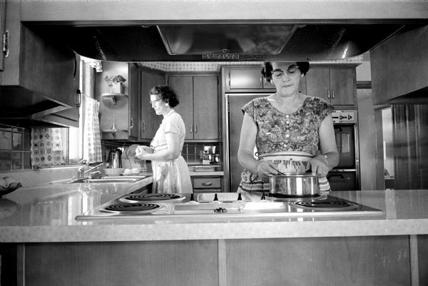 Doris, left, and Helen Saalsaa working together preparing dinner in their ultra-modern kitchen, which they designed for two cooks.