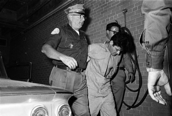 Captain Harry Wyatt, left, and Deputy Sheriff Mike Spencer bring prisoner Lawrence Nutley, of Chicago, to the Dane County jail in Madison. The prisoner was captured after the car he and two companions were in crashed during a police chase in Lyndon Station. They are all suspected of gunning down two Sauk county policemen in Lake Delton.