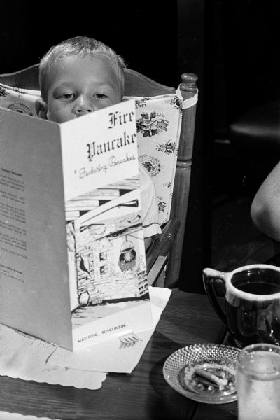 Looking at a menu at an open house and party at the Fireside Pancake House, 625 State Street, is Jimmy Jansen, 3. The open house is sponsored by the restaurant and United Cerebral Palsy of Dane County for children with cerebral palsy and their parents.