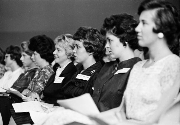 New teachers listening intently at an orientation meeting. The teachers, new to the Madison public schools, left to right (starting second from the left) are: Sue Gregg, Mendota school; Mary Joint, Lapham; Faith Koehl, Longfellow; Susan Verthein, Lowell; and Rae Carol Rocca, Randall. The teacher at either end of the image is not identified.