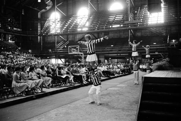 University cheerleaders performing in front of more than one thousand freshmen at the President's Convocation in the University of Wisconsin fieldhouse.