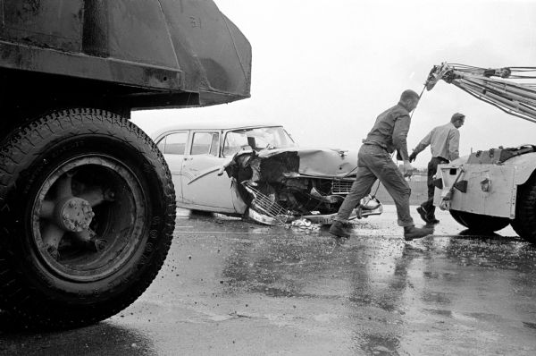 Police shown busy at the site of one of many crashes during a heavy rain. The driver of this car was injured when a trucker misjudged the distance during the downpour.