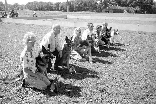 Winning dogs and their masters at the Lakeland Dog Training Club obedience trials at the Cambridge High School athletic field. Left to right are winners, first to sixth place: Diane Prueske, Posen, Illinois; Robert B. Blackhall, Sr., Milwaukee; Arlene L. Peterka, Menomonee Falls; Ted Clarke, Franklin Park, Illinois; Mrs. Joseph Lecher, Milwaukee; and Mildred Yohe, Minneapolis, Minnesota.