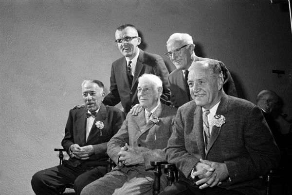 Four men who each earned nine athletic letters at the University of Wisconsin are honored by the National W Club, an organization of former Wisconsin lettermen. Shown seated (L-R) are John Messmer, Milwaukee; Harlen (Biddy) Rogers, Portage; and Rollie Barnum, Milwaukee. Standing (L-R) are Paul Pohle, president of the National W Club; and Rollie Williams, Iowa City, IA.