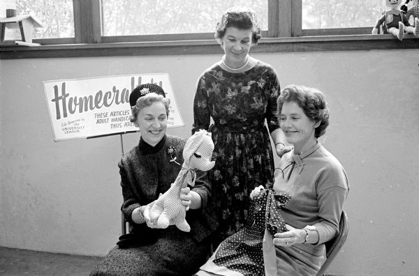 Maxine Backer, Eleanor Pritchard and Mildred Zimdars admire a stuffed animal and an apron which were made by the Dane County Homecrafters, an organization composed of handicapped adults.