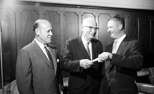 During a banquet to honor 66 men who had completed building trade apprenticeship training, new journeyman Kenneth Volkmann, right, receives a certificate of completion from, left to right: Nathan Feinsinger, University of Wisconsin law professor and noted mediator; and R.G. Knutson, state industrial commissioner. Feinsinger delivered the main address and Volkmann spoke on behalf of his former fellow apprentices.